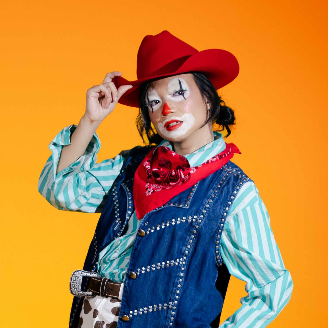 A rodeo clown costume — cow-print jeans, denim vest and a red felt hat.