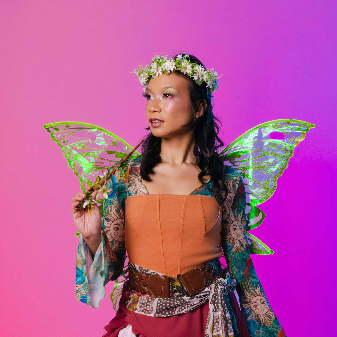 A fairy costume — flower crown, translucent wings and a patterned wrap.