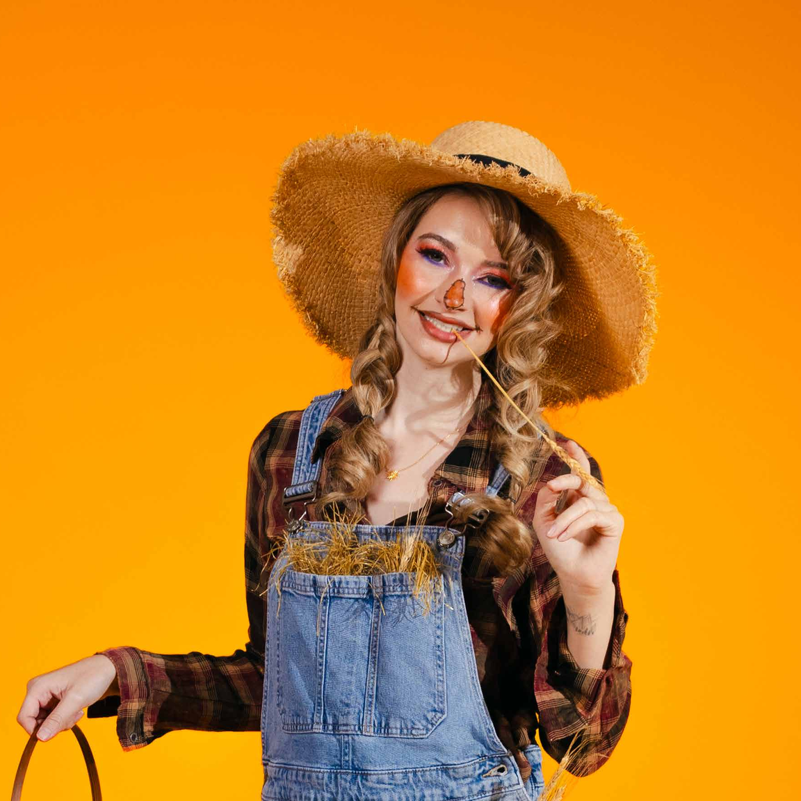 A scarecrow costume — patched denim overalls, a plaid shirt and a straw hat.